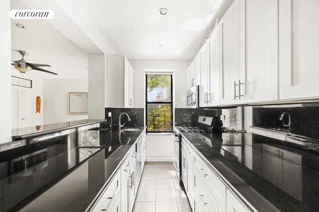 kitchen with light tile patterned flooring, appliances with stainless steel finishes, dark stone counters, decorative backsplash, and white cabinets