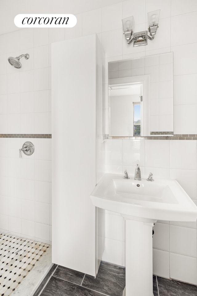 bathroom featuring backsplash, tiled shower, a sink, and tile walls