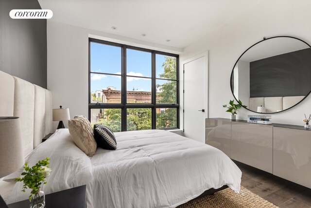 bedroom with multiple windows and dark wood-type flooring