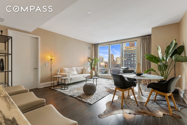 living room with baseboards, wood finished floors, visible vents, and a city view