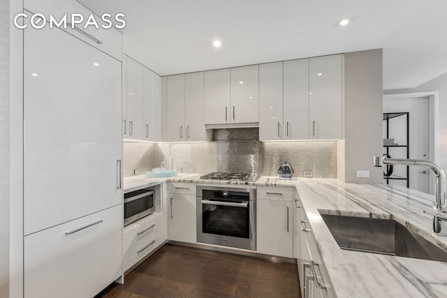50 Riverside Blvd Unit 19F, New York City, NY 10069 - kitchen with appliances with stainless steel finishes, a sink, modern cabinets, white cabinets, and dark wood-type flooring