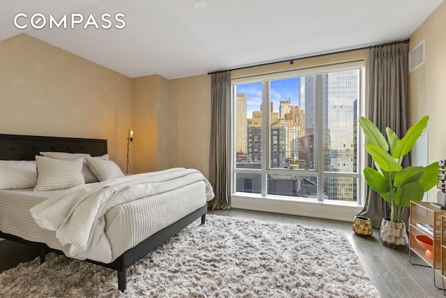 bedroom with wood finished floors and a city view