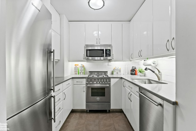 kitchen with sink, white cabinets, dark tile patterned floors, and high quality appliances