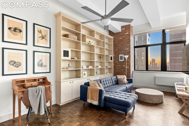 living area with ceiling fan, dark parquet flooring, and beamed ceiling