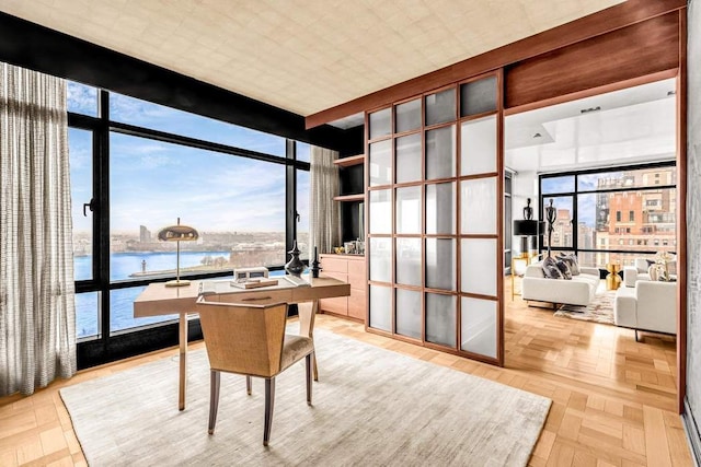 home office featuring parquet flooring, a wall of windows, french doors, and a water view