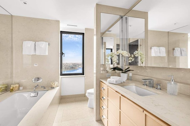 bathroom featuring a relaxing tiled tub, vanity, tile patterned floors, and toilet