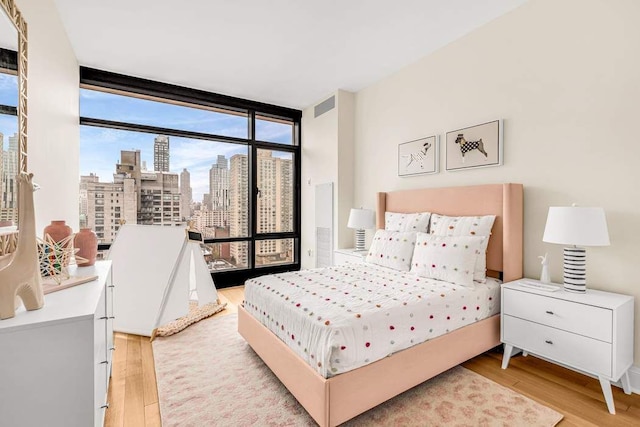 bedroom featuring floor to ceiling windows and light hardwood / wood-style floors