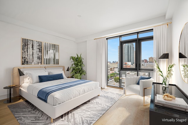 bedroom with access to outside, a view of city, and wood finished floors