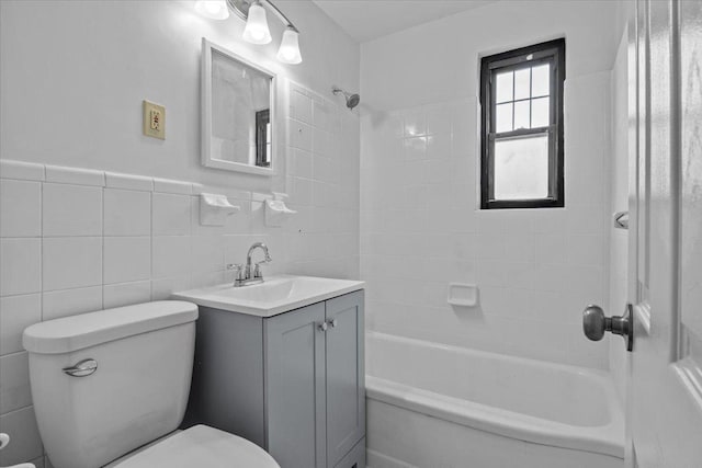bathroom with tile walls, toilet, vanity, wainscoting, and shower / bathtub combination