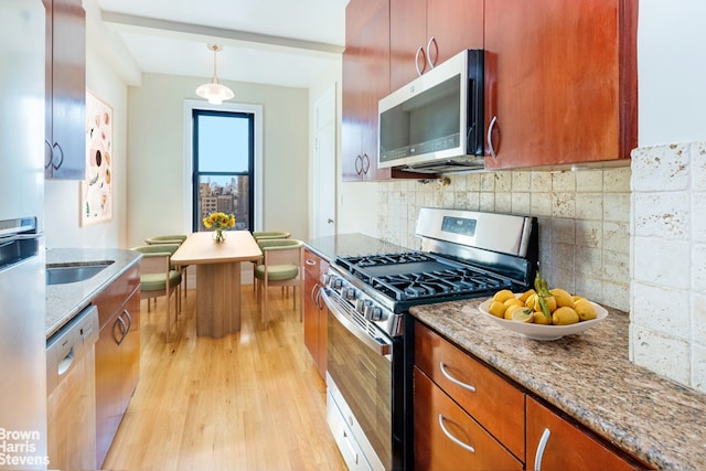 kitchen featuring light stone countertops, appliances with stainless steel finishes, light hardwood / wood-style flooring, and decorative light fixtures