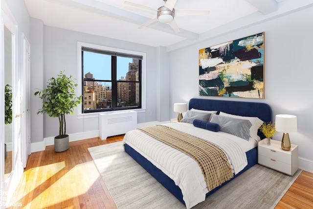 bedroom with radiator heating unit, baseboards, and wood finished floors