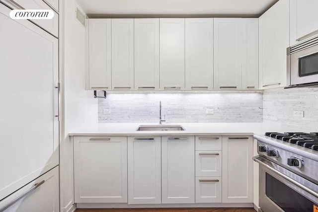 kitchen with stainless steel appliances, white cabinetry, sink, and decorative backsplash