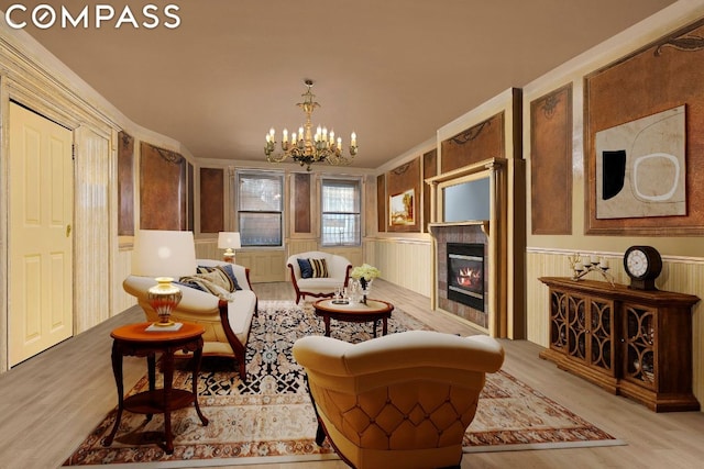 living area with an inviting chandelier, a tile fireplace, and light wood-type flooring