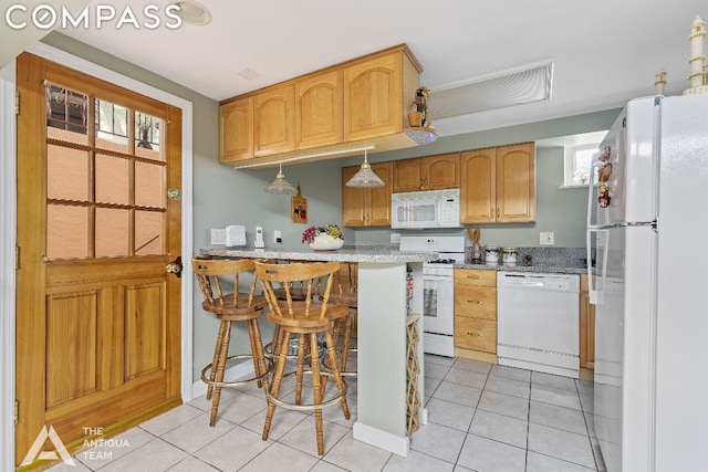 kitchen featuring light stone countertops, a kitchen bar, light tile patterned floors, and white appliances