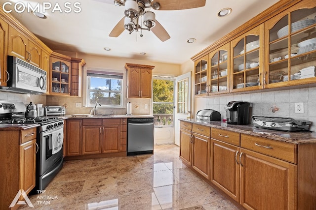 kitchen with sink, tasteful backsplash, dark stone counters, ceiling fan, and stainless steel appliances