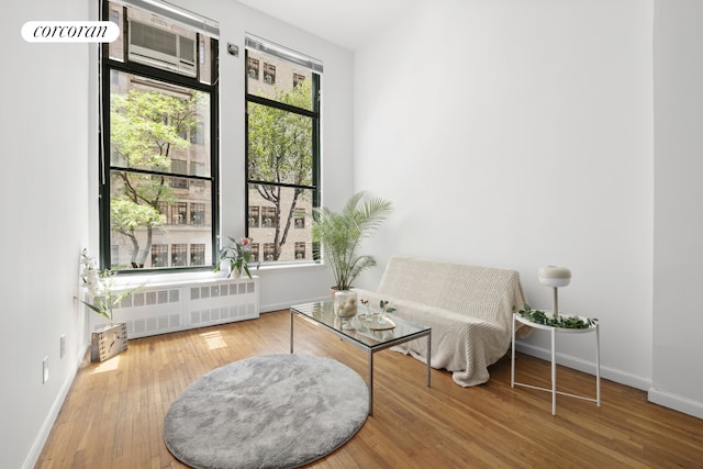 sitting room featuring radiator, wood-type flooring, and baseboards