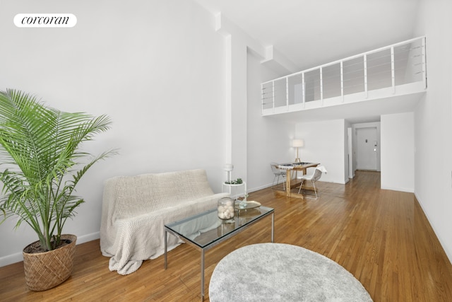 living area with a towering ceiling and hardwood / wood-style floors