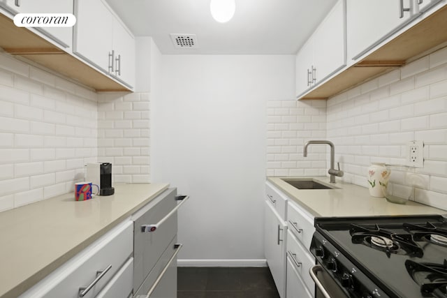 kitchen featuring tasteful backsplash, gas range, sink, and white cabinets