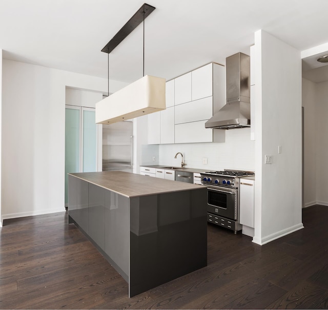 kitchen with wall chimney exhaust hood, premium appliances, modern cabinets, dark wood-style floors, and tasteful backsplash