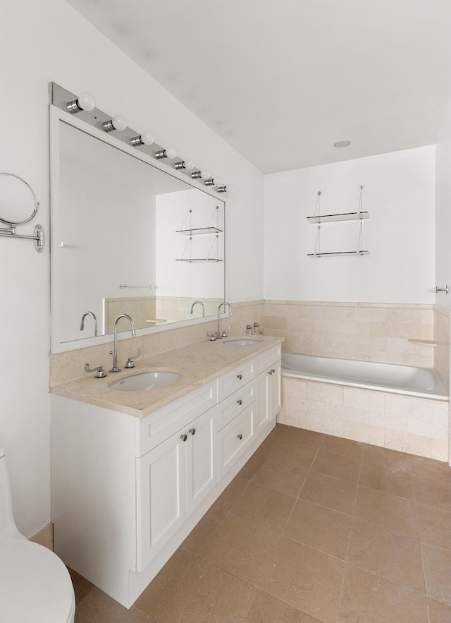bathroom featuring a relaxing tiled tub, double vanity, toilet, and tile patterned flooring