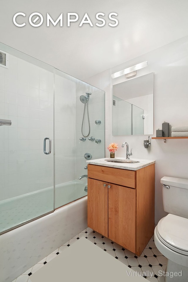 bathroom featuring vanity, toilet, tile patterned floors, visible vents, and bath / shower combo with glass door
