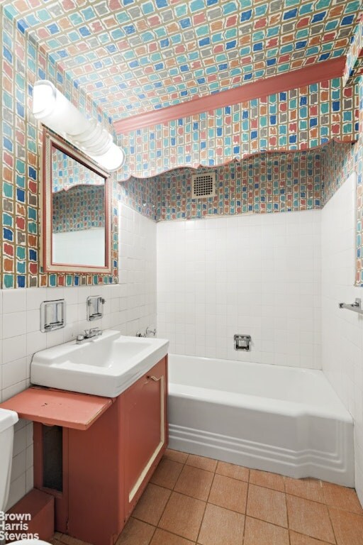 bathroom with tile patterned flooring, vanity, tile walls, a bathtub, and toilet