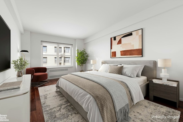 bedroom with dark hardwood / wood-style floors and radiator heating unit