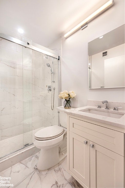 bathroom with toilet, vanity, and a shower with door