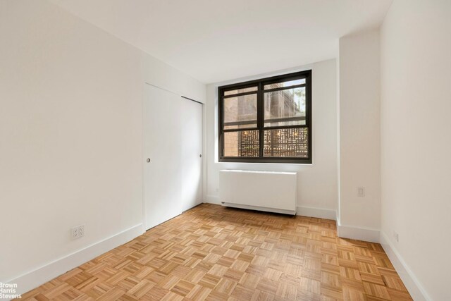 spare room featuring light parquet floors, radiator heating unit, and ornamental molding