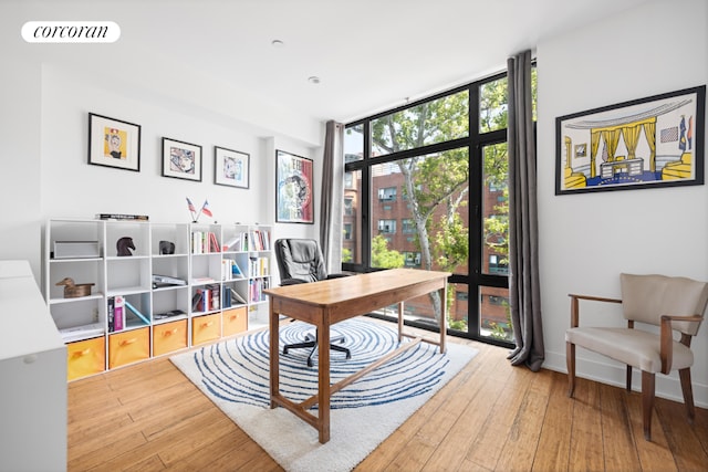 office space with baseboards, wood finished floors, visible vents, and floor to ceiling windows