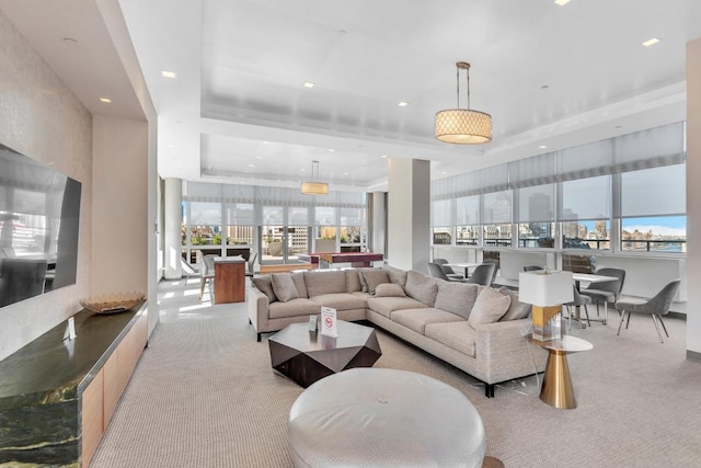 living room with a raised ceiling and light carpet