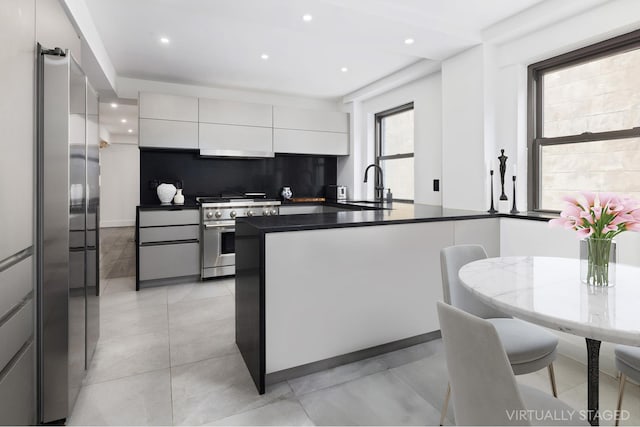 kitchen featuring stainless steel appliances, backsplash, white cabinets, a sink, and modern cabinets