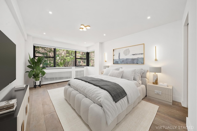 bedroom featuring light wood finished floors, radiator heating unit, and recessed lighting