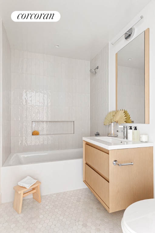 full bathroom with toilet, tile patterned floors, tiled shower / bath, and vanity