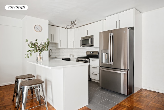 kitchen featuring a breakfast bar, kitchen peninsula, sink, stainless steel appliances, and white cabinets