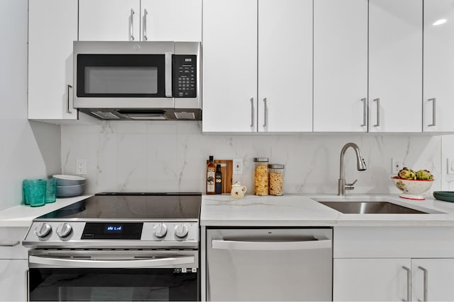 kitchen with tasteful backsplash, appliances with stainless steel finishes, white cabinetry, and a sink