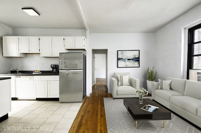 interior space with sink, white cabinetry, light tile patterned floors, stainless steel refrigerator, and white dishwasher