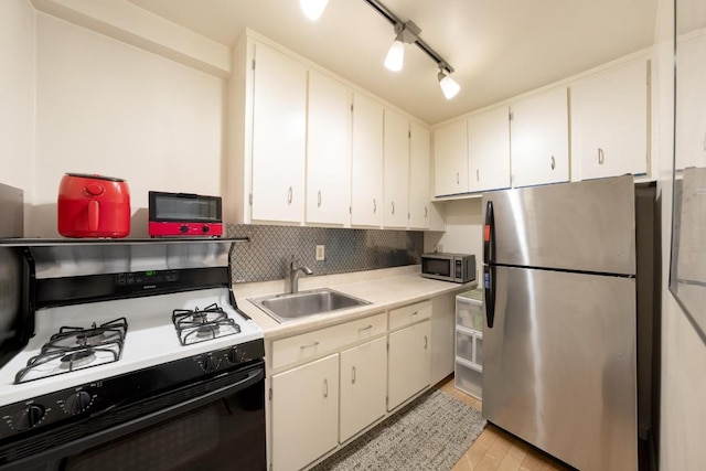 kitchen with appliances with stainless steel finishes, sink, white cabinetry, and rail lighting