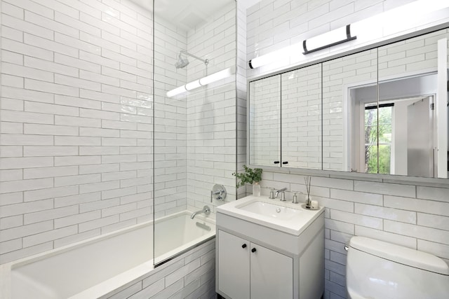 full bathroom with tile walls, vanity, tiled shower / bath combo, and toilet