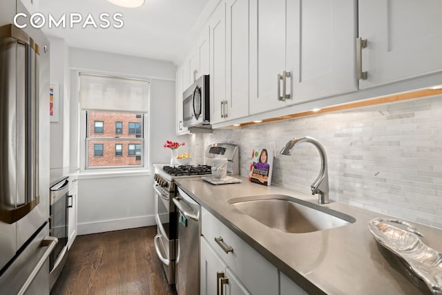 kitchen with backsplash, dark wood-type flooring, stainless steel appliances, white cabinetry, and a sink