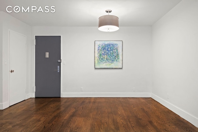 empty room featuring dark wood finished floors and baseboards