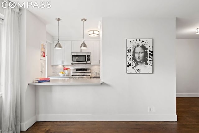 kitchen with stainless steel microwave, tasteful backsplash, gas stove, white cabinets, and dark wood-style flooring