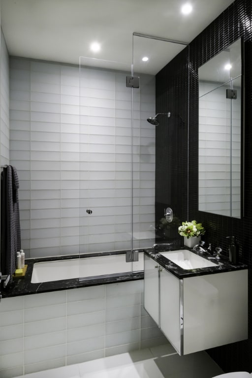 bathroom with a shower with door, vanity, and tile walls