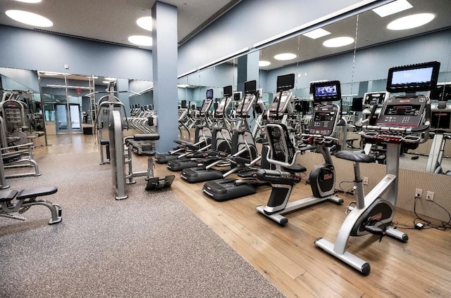 gym featuring hardwood / wood-style flooring and a towering ceiling