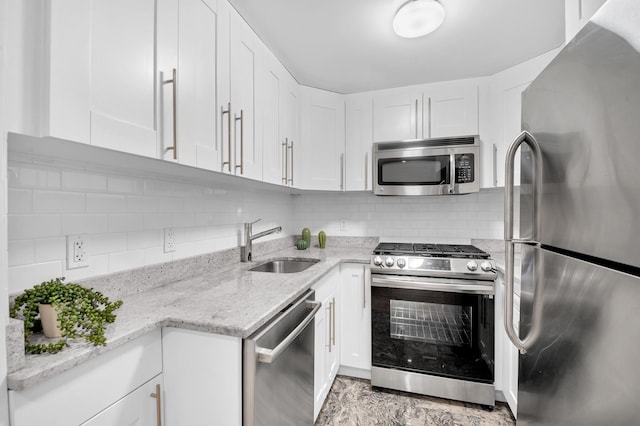 kitchen featuring stainless steel appliances, tasteful backsplash, a sink, and white cabinetry