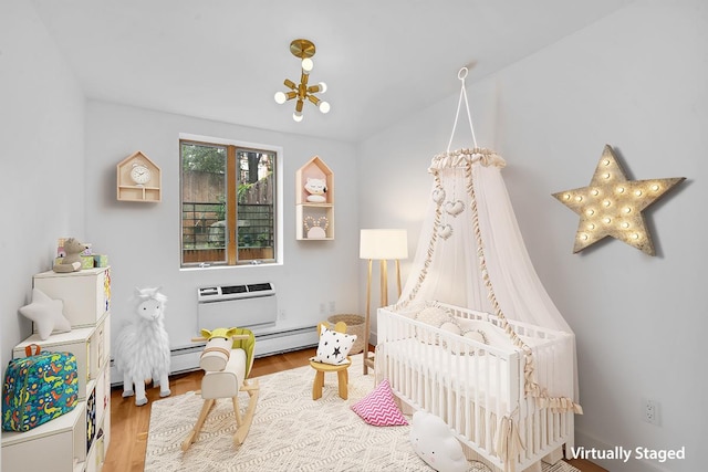 game room with a notable chandelier, baseboard heating, wood finished floors, and a wall mounted AC