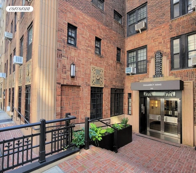 doorway to property featuring cooling unit, brick siding, and an AC wall unit