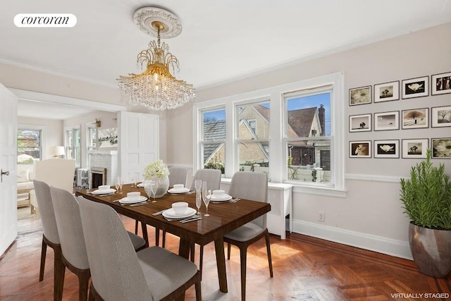 dining area featuring an inviting chandelier, dark parquet flooring, a fireplace, and crown molding