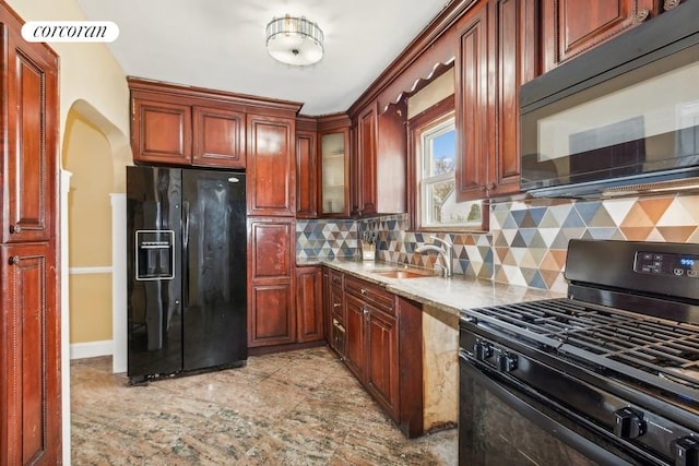 kitchen with light stone countertops, sink, backsplash, and black appliances