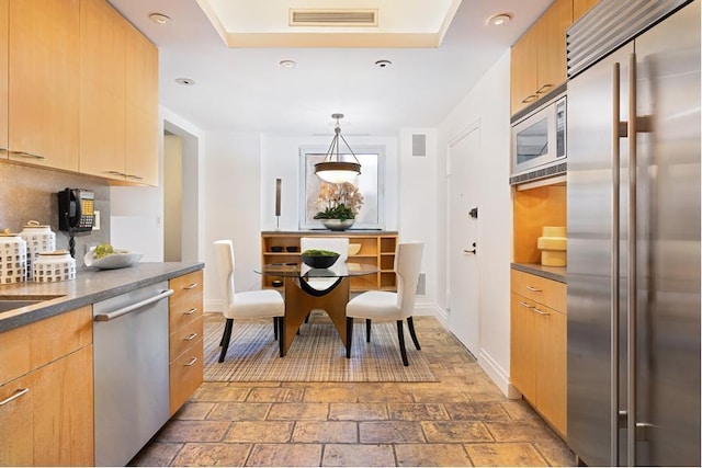 kitchen featuring visible vents, built in appliances, dark countertops, and stone finish flooring